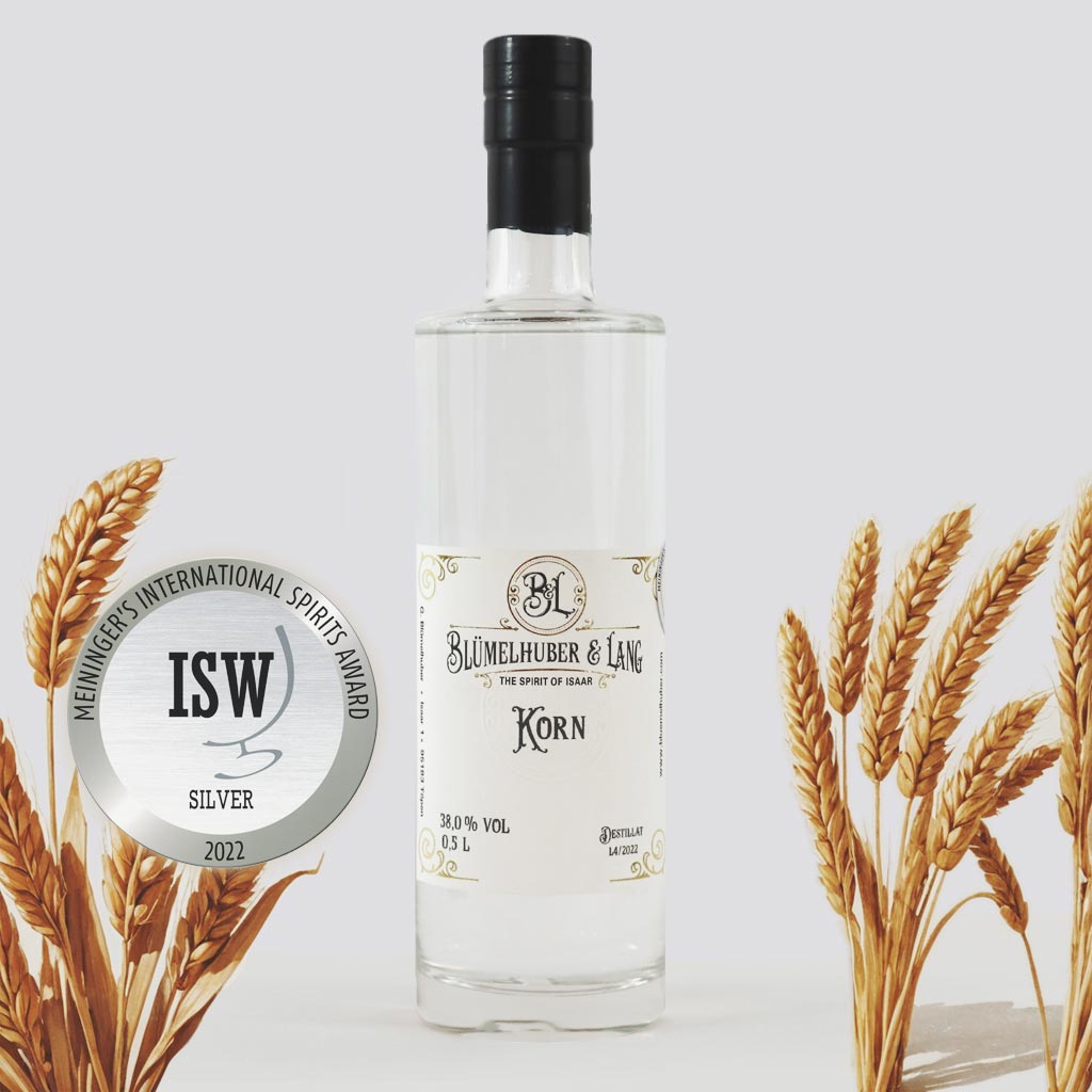 Produktabbildung Blümelhuber & Lang Korn - Flasche vor grauem Hintergrund mit Weizenähren. Zudem ist das silberne ISW-Siegel zu sehen.